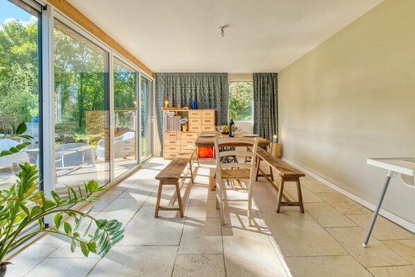 A modern interior with a dining area, wooden furniture, and large glass doors leading to an outdoor space. - The Longère of Astérius – Relaxing Stay in an Eco-Friendly Holiday Home in Saint-Astier (Saint-Astier)