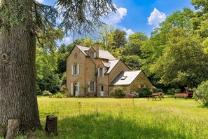 A stone house with a sloped roof, surrounded by a grassy yard and trees. - Forest Cottage 'Maison forestière Pleine Nature Kerdary' with Private Terrace, Garden & Wi-Fi (Nivillac)