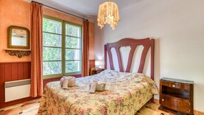 Un dormitorio con cama, ventana, espejo y mesita de noche de madera.
