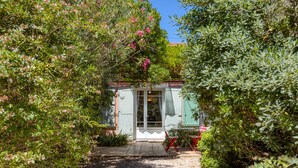 Un sendero en un jardín que lleva a un edificio con una puerta y ventanas.