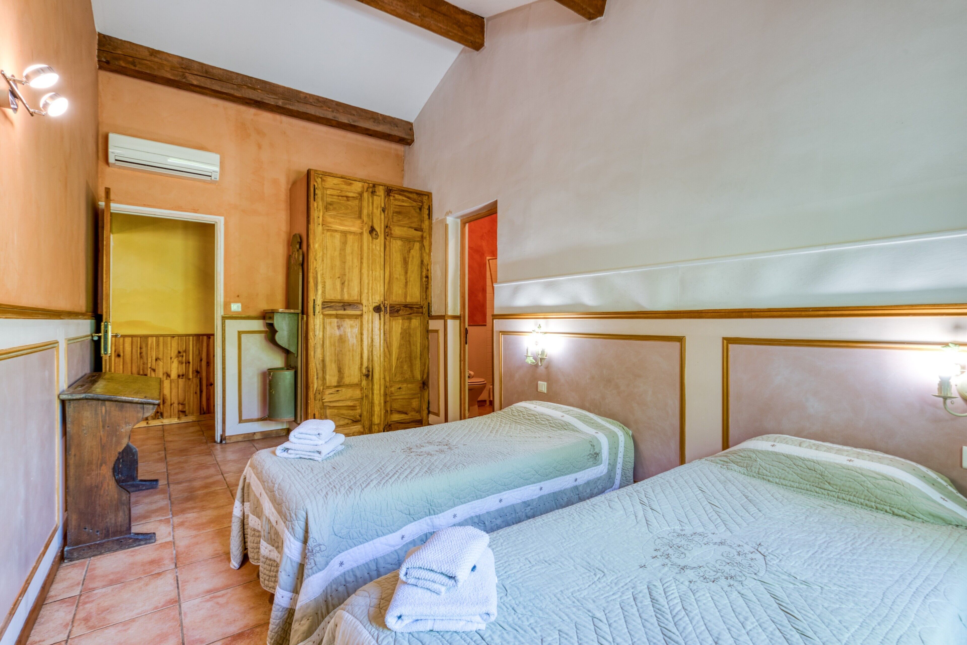 Une chambre avec deux lits, une armoire en bois et un bureau.