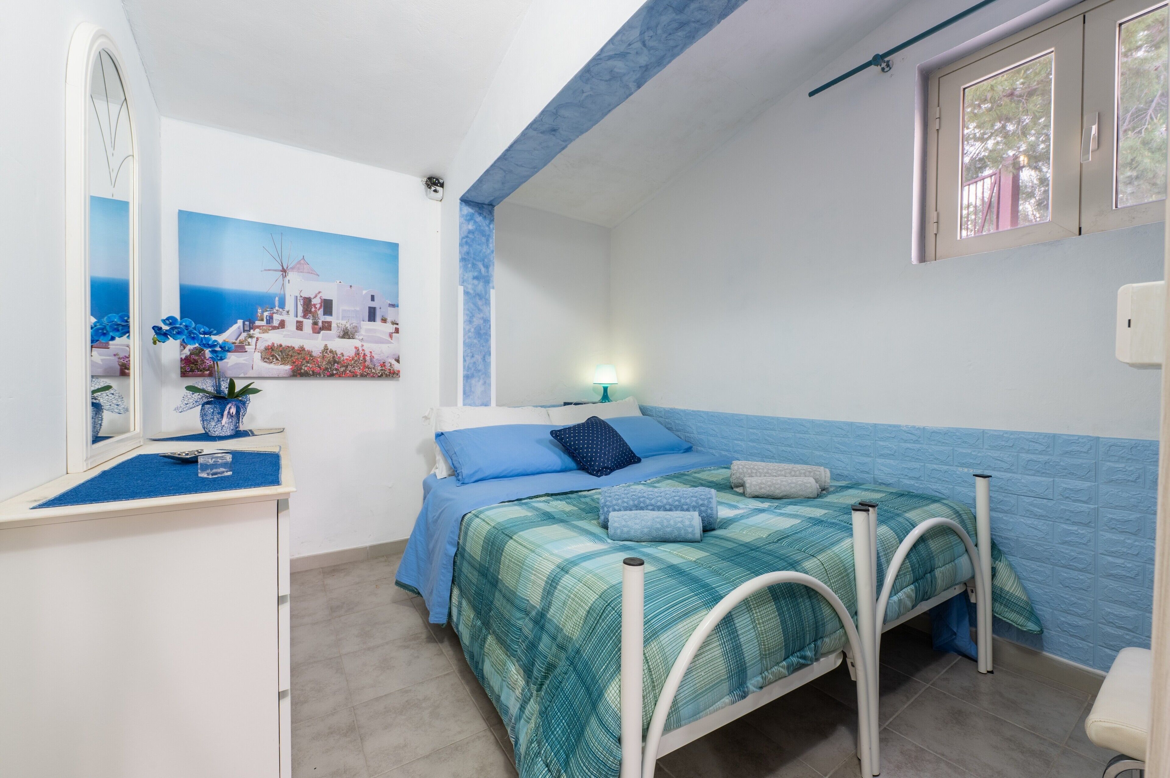 Une chambre à coucher avec un lit, un bureau, un miroir et une fenêtre.