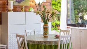 A dining area with a round table, chairs, a vase with flowers, and a wall with framed pictures. - Holiday Home 'Casa Montereale' with Sea View, Private Terrace and Wi-Fi (Realmonte)