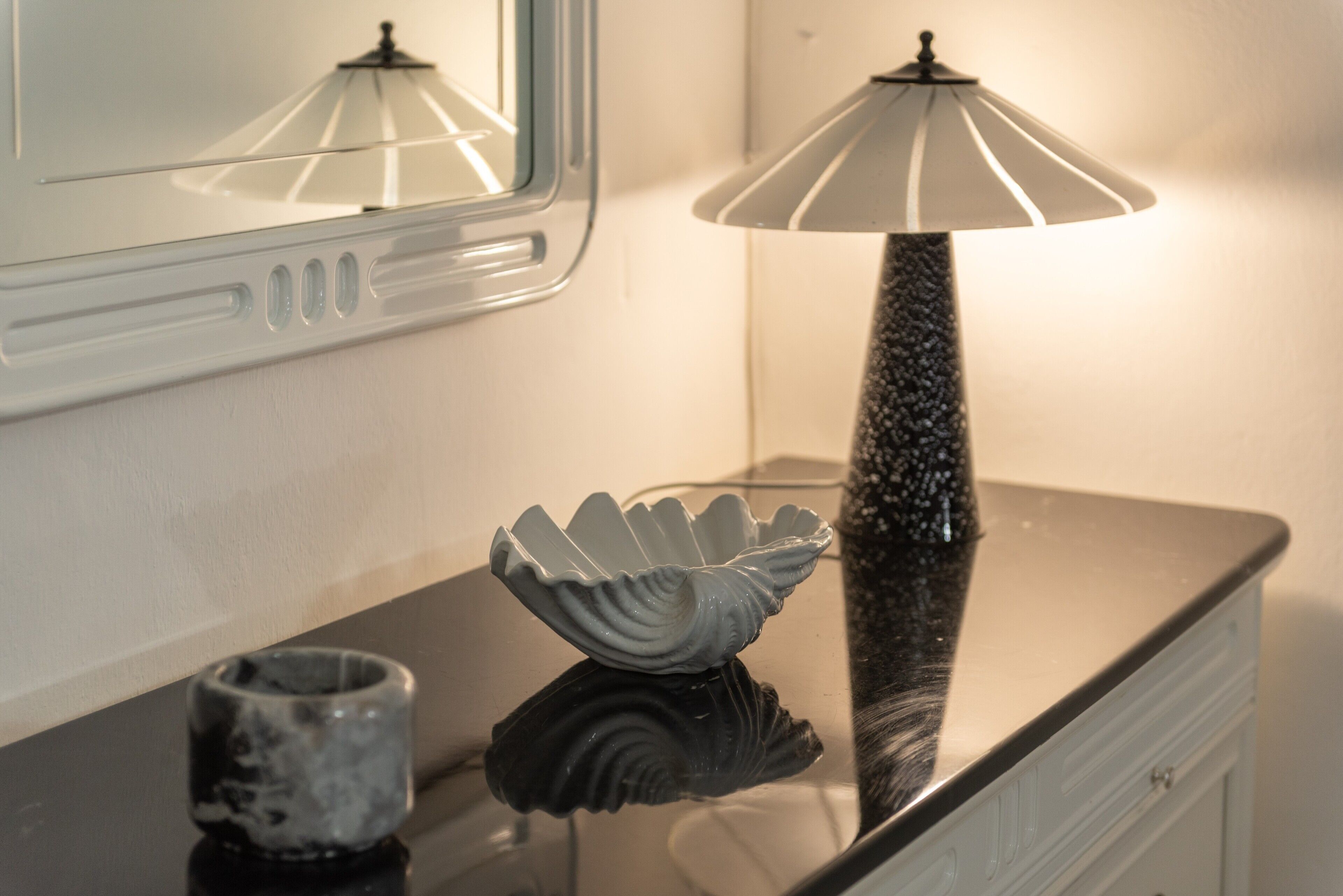 A bathroom vanity with a mirror, a lamp, and decorative items.