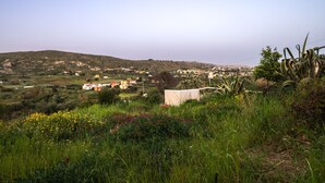 A rural landscape with a hill, vegetation, and a white building in the foreground. - Holiday Home 'Casa Montereale' with Sea View, Private Terrace and Wi-Fi (Realmonte)