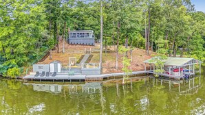 Un chalet au bord du lac, avec un quai, un petit bateau et un espace salon abrité.