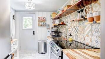 Una cocina con armarios blancos, encimera de madera y un salpicadero con diseño.