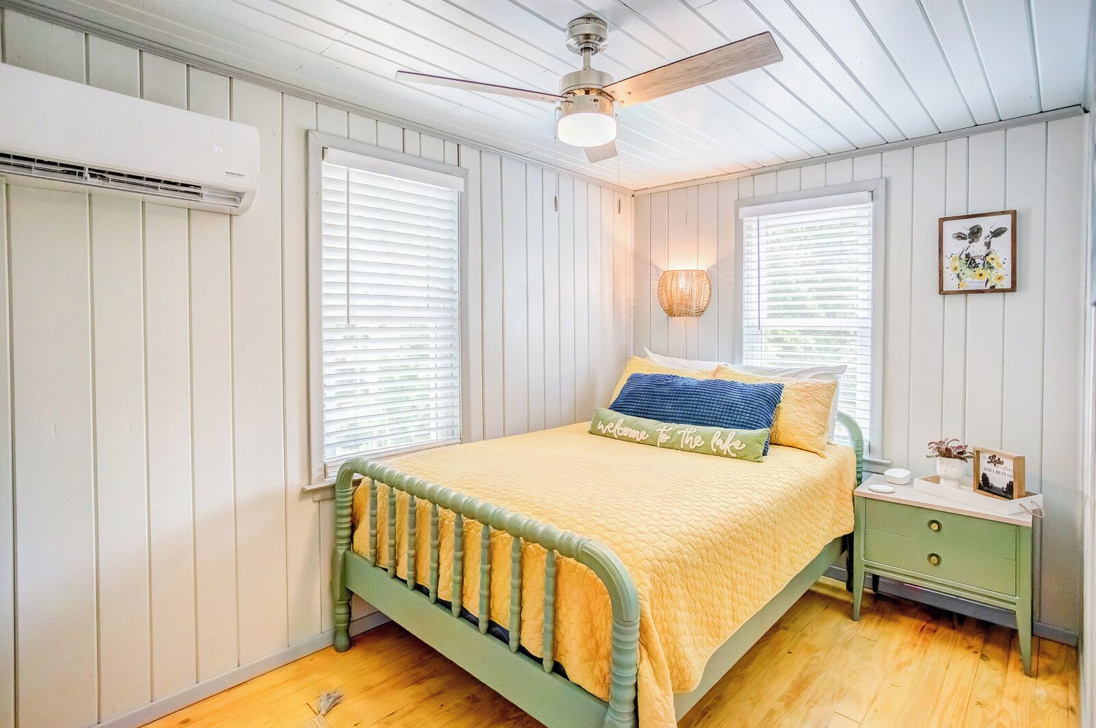 Un dormitorio con cama, mesita de noche, lámpara y ventilador de techo.
