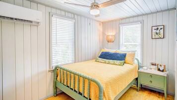 Un dormitorio con cama, mesita de noche, lámpara y ventilador de techo.