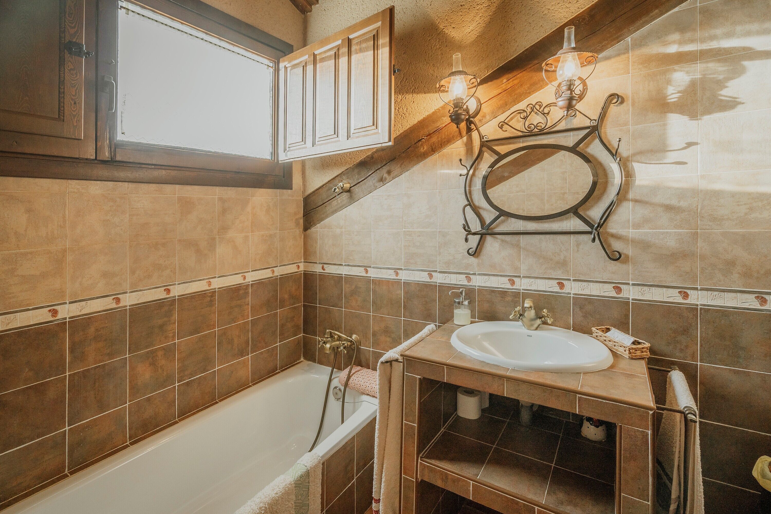 A bathroom with a bathtub, a sink, a towel rack, and a decorative wall light fixture.