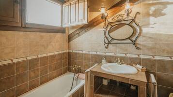 A bathroom with a bathtub, a sink, a towel rack, and a decorative wall light fixture.