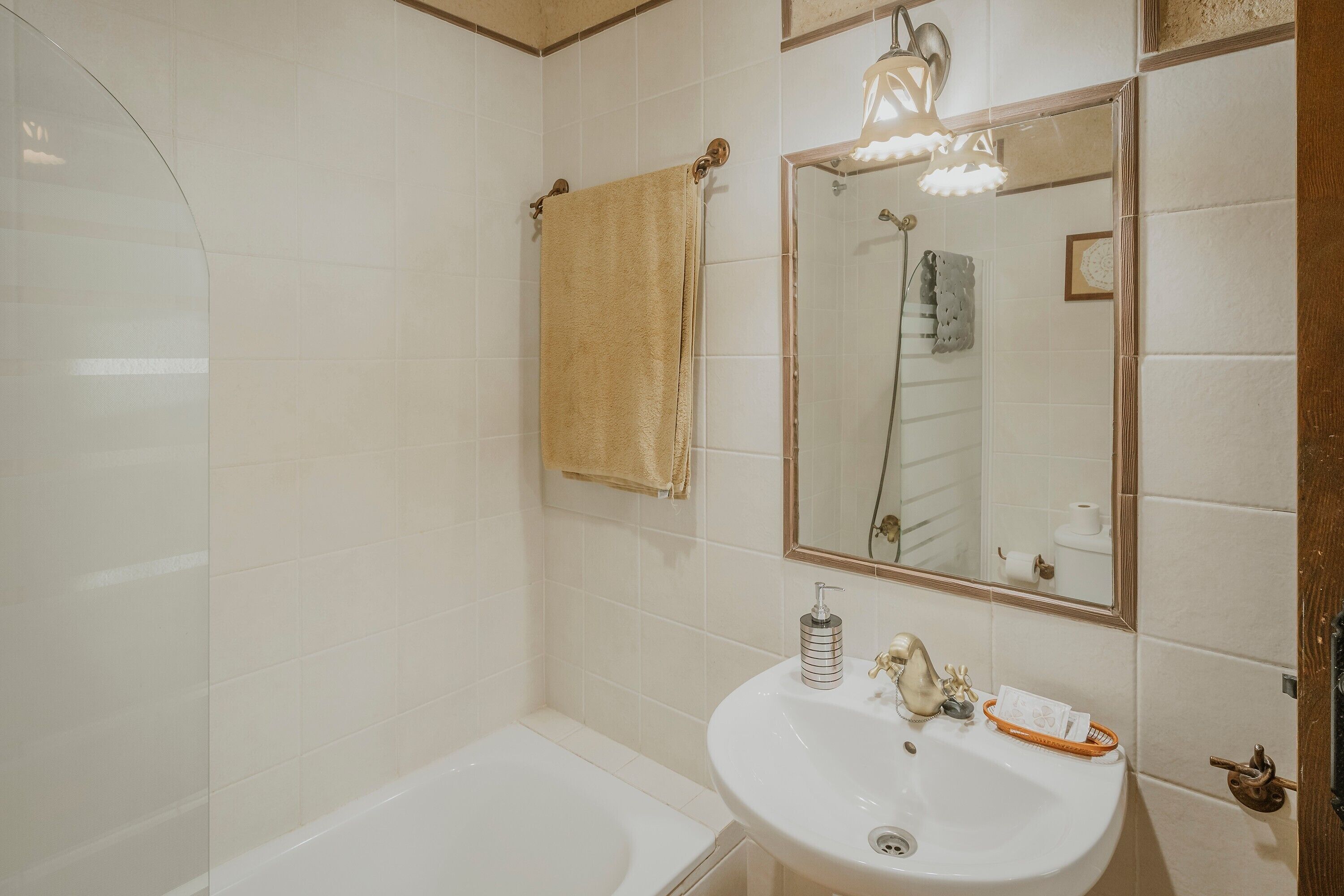 A bathroom with a bathtub, a sink, a mirror, and a towel hanging on the wall.