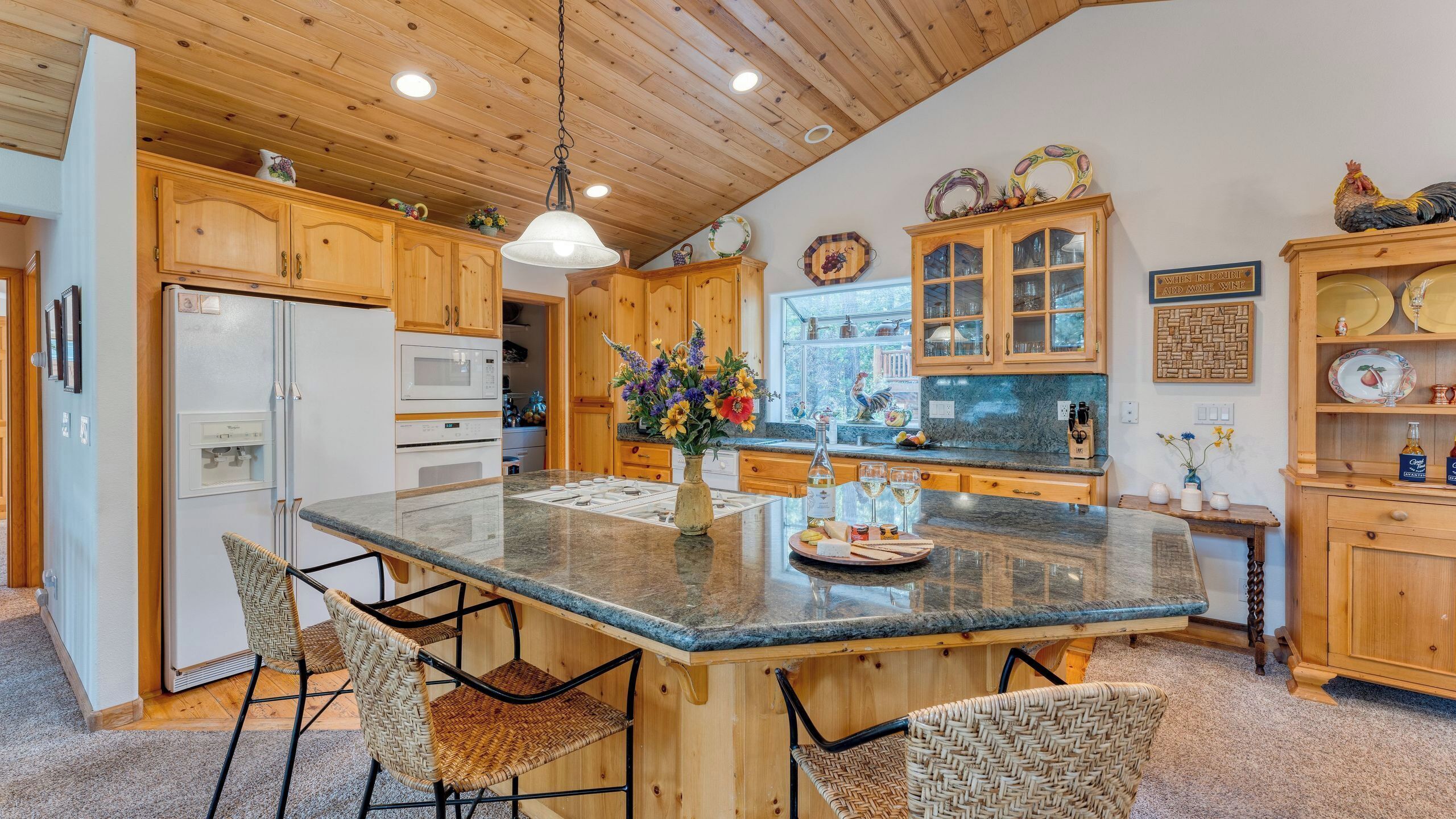 A kitchen with wooden cabinets, a granite countertop, and a central island with chairs.