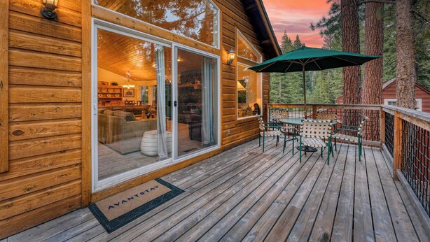 A wooden cabin with a deck, large windows, and a green umbrella. - Tahoe Vista by Avantstay Central Location + Patio (Tahoe Vista)