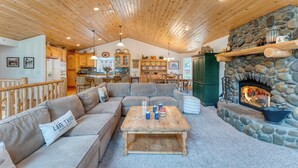 A cozy living room with a stone fireplace, wooden ceiling, and a sofa with a pillow labeled "Lake Tahoe." - Tahoe Vista by Avantstay Central Location + Patio (Tahoe Vista)