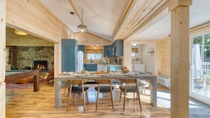 A wooden interior with a dining area, kitchen, and stone fireplace.