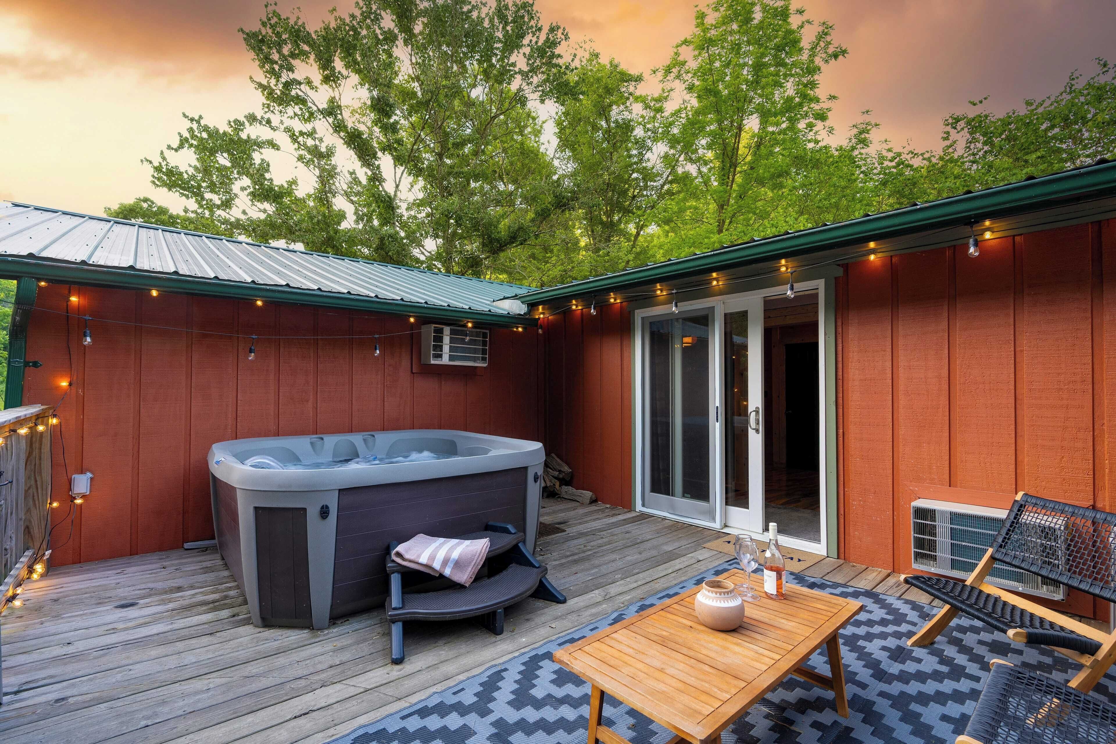A wooden deck with a hot tub, a table with chairs, and string lights.