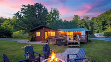 Una cabaña con terraza, mobiliario exterior y una chimenea.
