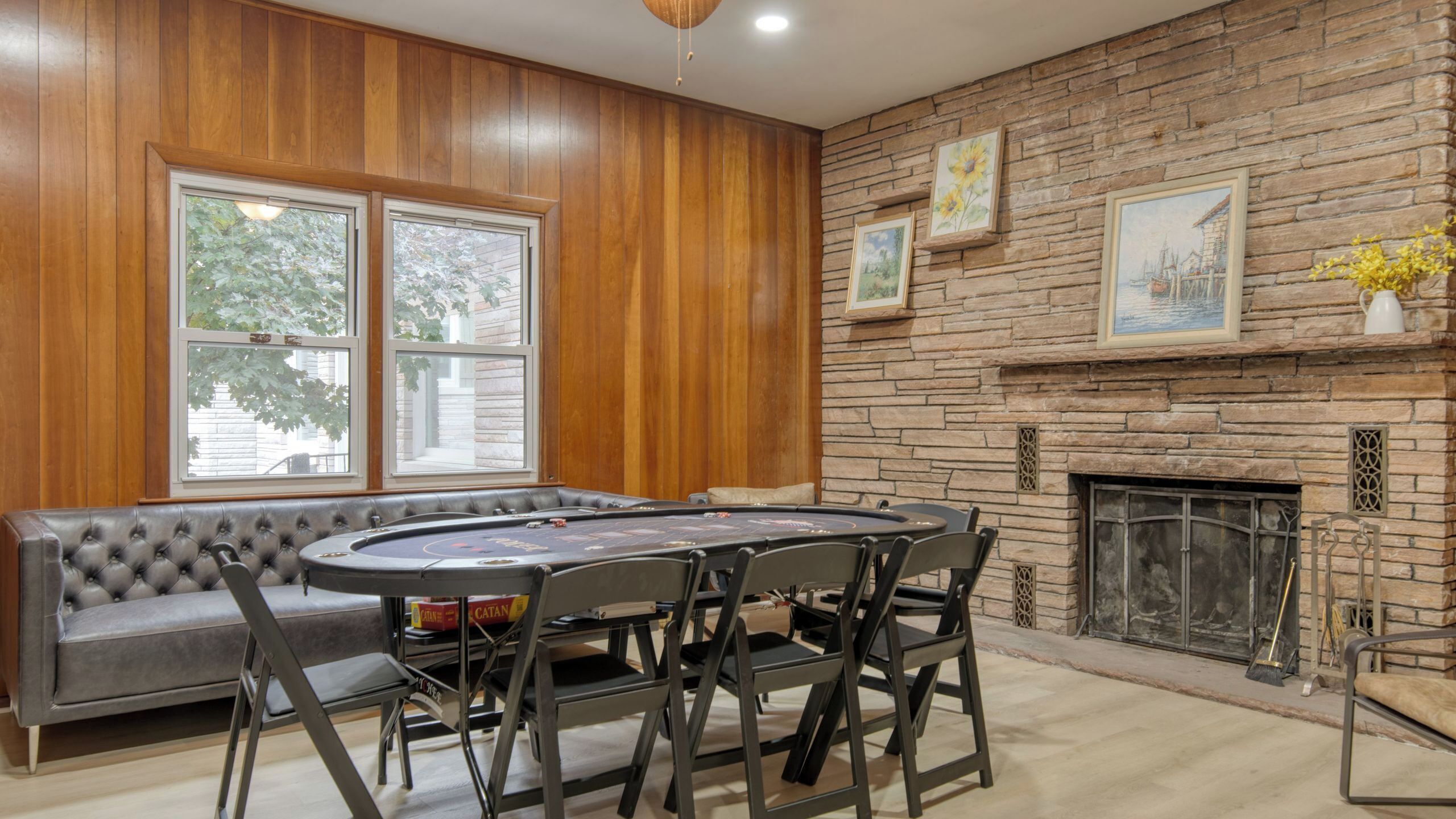 Una habitación con una mesa de póker, chimenea y pared de piedra.