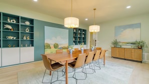 A dining area with a wooden table, chairs, and pendant lights.