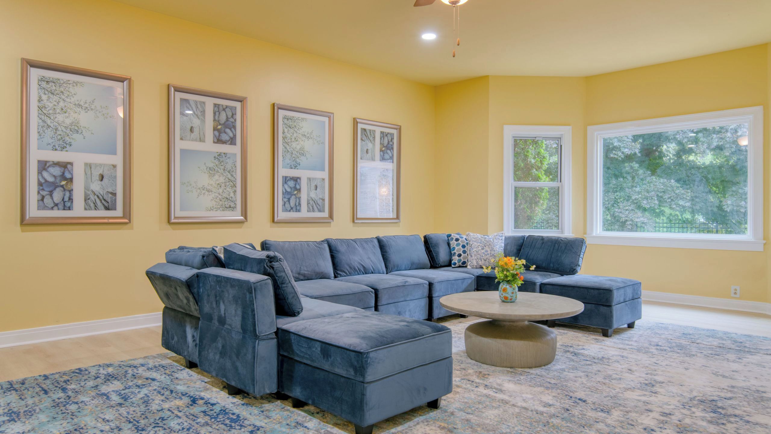 A living room with a sectional sofa, a round coffee table, and framed artwork on the walls.