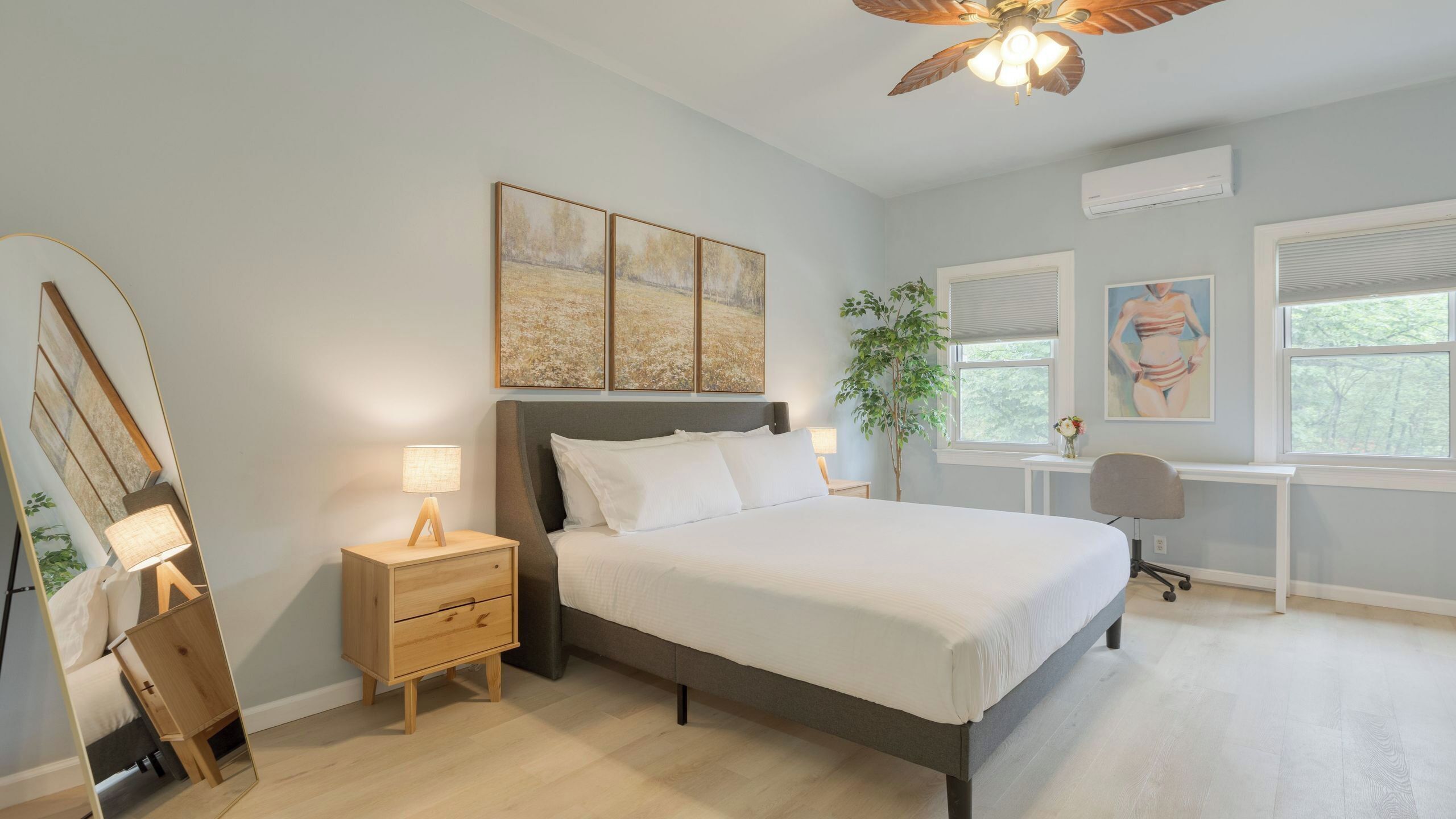 A bedroom with a bed, bedside tables, a desk, and a ceiling fan.