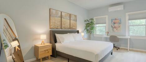 A bedroom with a bed, bedside tables, a desk, and a ceiling fan.