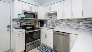 A modern kitchen with white cabinets, stainless steel appliances, and a tiled backsplash.
