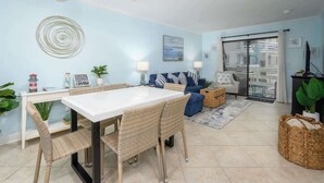 A living room with a dining table, wicker chairs, a sofa, and a TV.