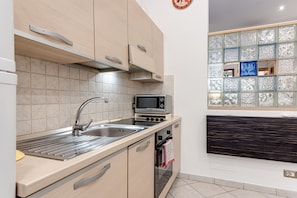 Una cocina moderna con horno empotrado, microondas y pileta de acero inoxidable.