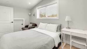 Un dormitorio con cama, escritorio, silla, ventana con persianas y puerta.