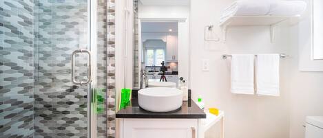 Un baño moderno con cabina de ducha de vidrio, un lavabo blanco y un inodoro.