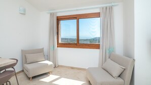 Una habitación con dos sofás, una mesa y una ventana con cortinas.
