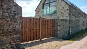 Un edificio de piedra con una cerca de madera y un ventanal grande.