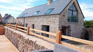 Una casa de piedra con terraza de madera y valla de madera.