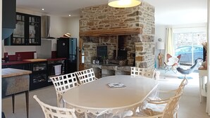 Una cocina moderna con chimenea de piedra, sillas de comedor blancas y una lámpara colgante.