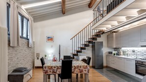 Una cucina moderna con forno integrato, un'area pranzo con tovaglia fantasia e una scala che conduce a un piano superiore.