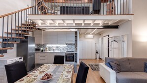 Un appartamento moderno con cucina, zona pranzo e una scala che conduce a una camera da letto in soppalco.