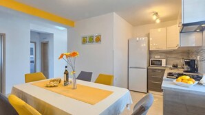 A modern kitchen with a built-in oven, microwave, and gas stove. There is a dining table with chairs, and a vase with flowers on it. - Apartment Viola in center of Medulin for 6 person (Medulin)