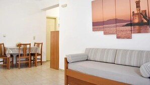 Ein Zimmer mit Esstisch, Stühlen, einer Couch und einem an der Wand hängenden Gemälde eines Leuchtturms.