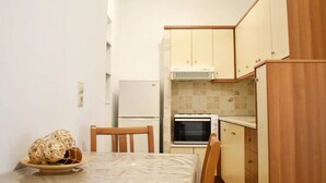 Eine kleine Küche mit Esstisch, Stühlen, einem Kühlschrank, einem Backofen und Holzschränken.
