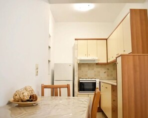 A compact kitchen with a refrigerator, oven, and wooden cabinets.