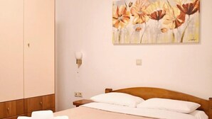 Una habitación de hotel con cama, armario, un cuadro y mesita de noche.