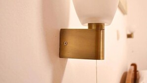 Una lámpara de pared con pantalla de vidrio esmerilado y base de latón.