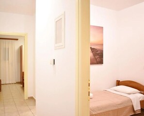 A bedroom with a bed, a picture on the wall, and a door leading to another room.