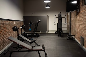 A gym with exercise equipment, a bench, and a brick wall. - Apartment 'Pardo 3' with Private Terrace, Wi-Fi and Air Conditioning (León)