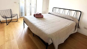 A bedroom with a bed, a chair, and a view of the outside. - Suite&Chic Apartment (Bari)