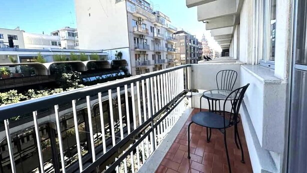A balcony with a table and chairs, overlooking a train track and adjacent buildings. - Suite&Chic Apartment (Bari)