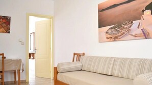 A room with a wooden sofa, a dining table, and a painting on the wall. - Apartment 'Manolika Studio 4' with Sea View, Wi-Fi and Air Conditioning (Kythnos)
