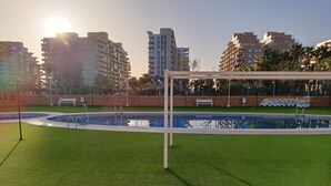 Une piscine entourée d’une pelouse, agrémentée de bancs et d’une structure en forme de pergola.